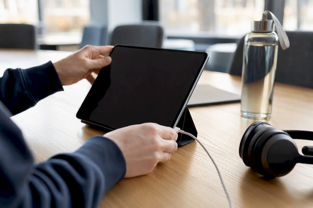 Hände justieren das Tablet und ziehen das Kabel ab